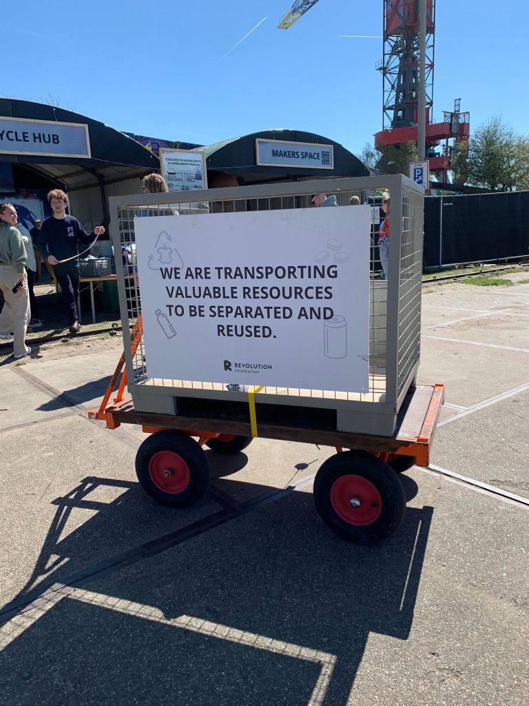An empty wire fence trolley cart with a sign that reads: "We are transporting valuable resources to be separated and reused."
